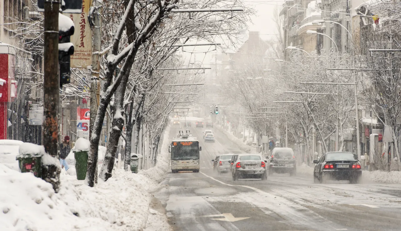 Bucharest in winter is sometimes snowy, as you can see in this image which features cars and buses driving along an icy road.