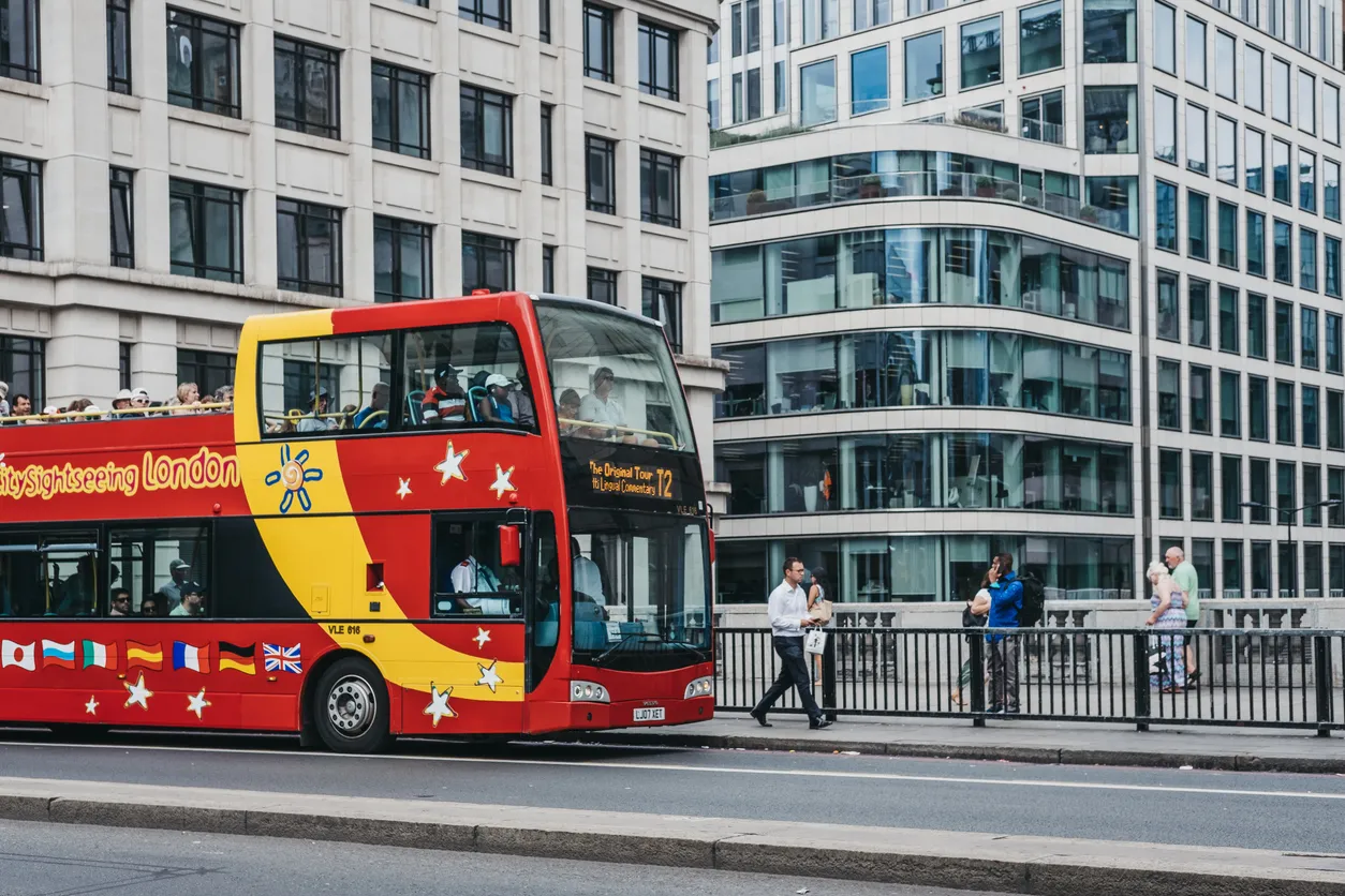 London, UK - July 24, 2018: City Sightseeing Hop-On Hop-Off Tour Bus collecting customers on London Bridge, London. Open roof tour buses are very popular amongst tourists in London.
