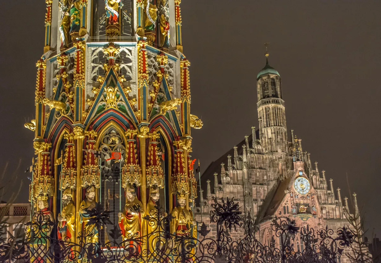 One of the most beautiful landmarks in Nuremberg - Schöner Brunnen in the foreground, and the Frauenkirche in the background, pictured during Traditional Christmas market in the town.