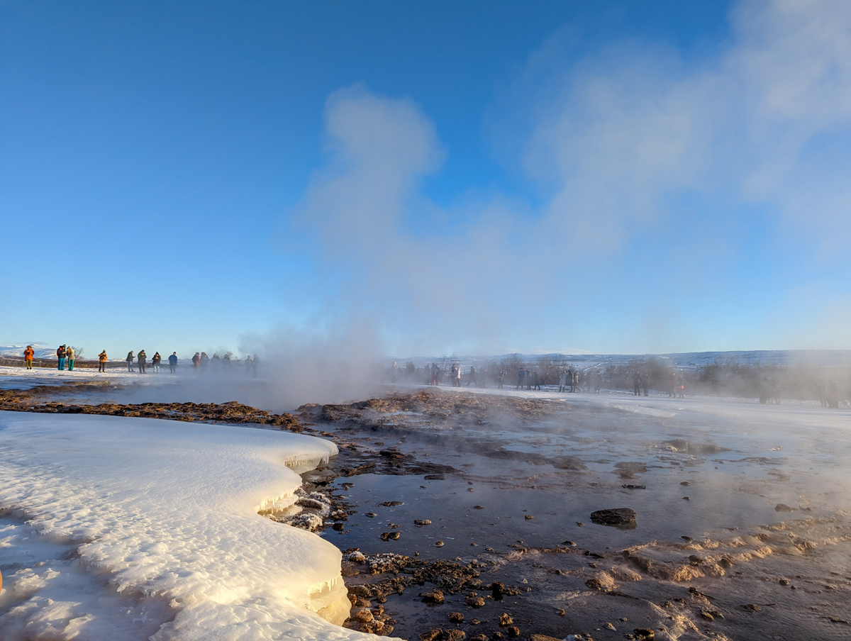 Laugarvatin Fontana, thermal waters where bread is baked. Steam rises off the hot pool and snow lines the edge. 