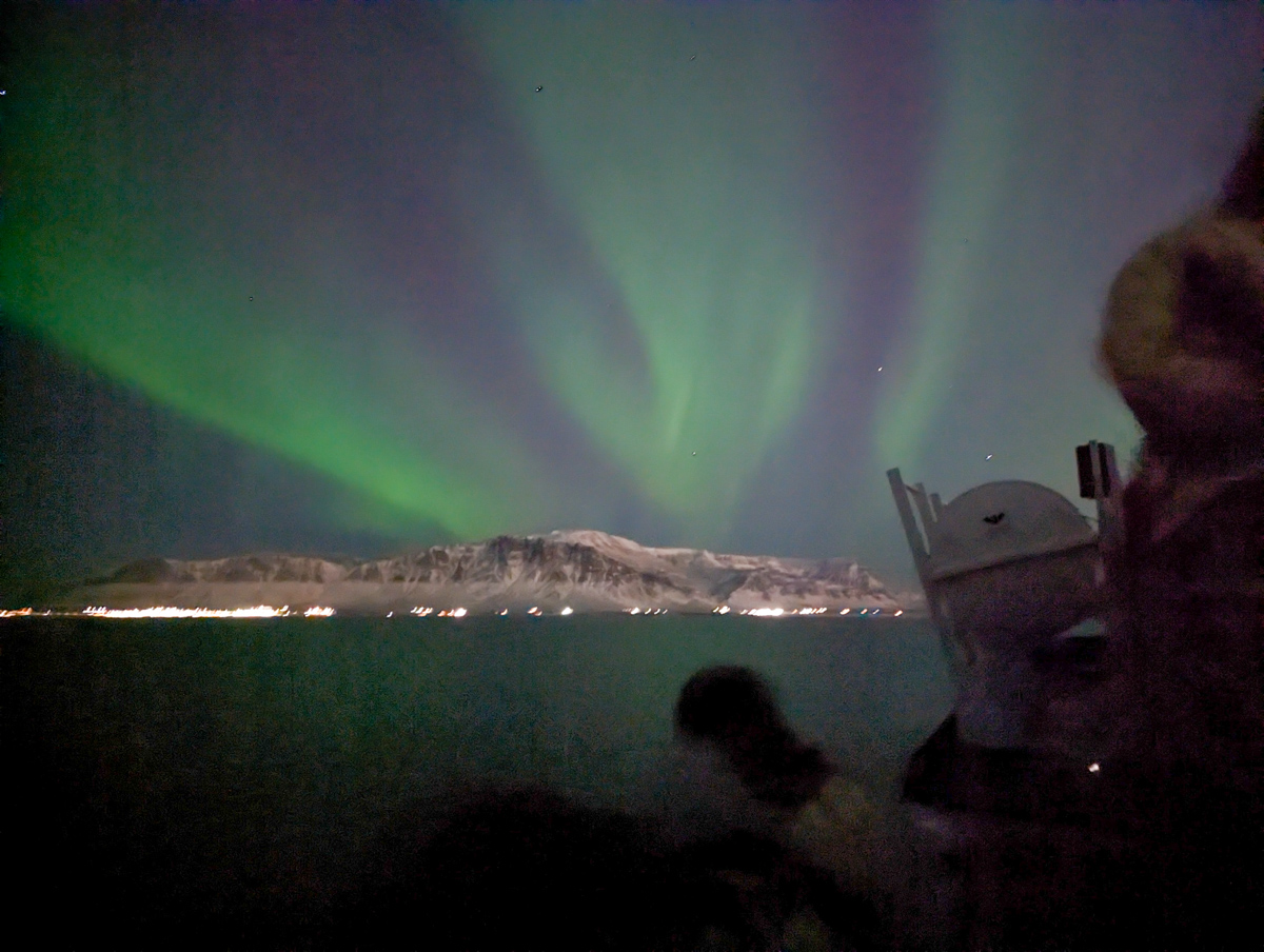Northern Lights illuminating the sky above the mountains of Reykjavik.