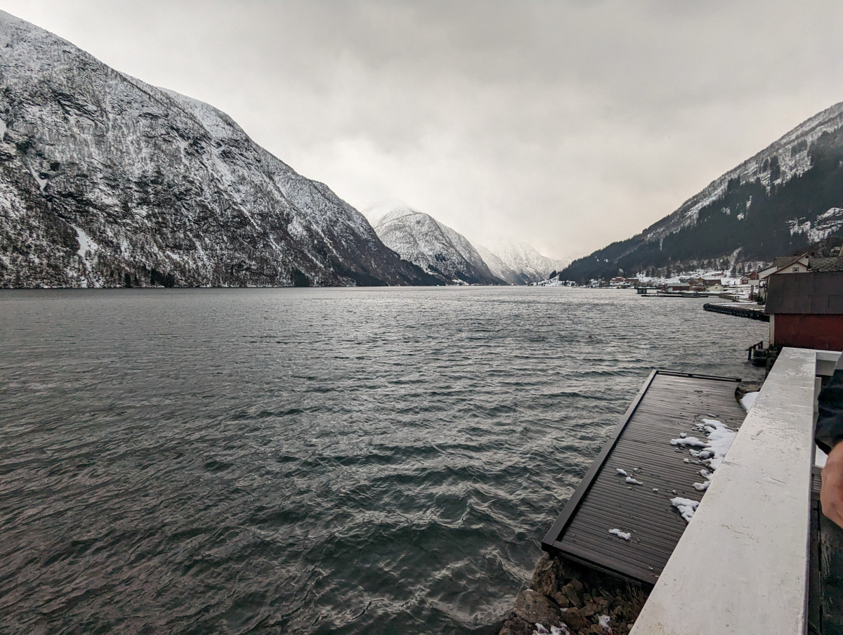Looking out from the fjords of Fjaerland Fjordstove Hotel. Snow covered mountains in the background and water in the foreground.